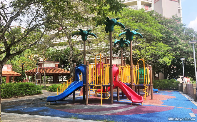 A colourful climbing and slide structure with palm-tree-themed posts at Tampines Tree Garden.