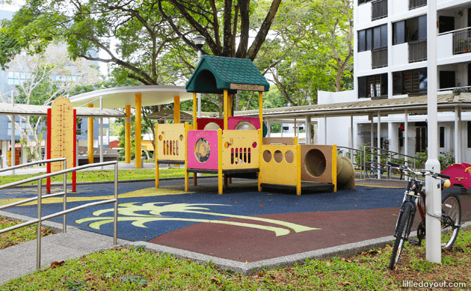 A low yellow and red play structure with a small slide and climbing panels at Commonwealth Crescent.