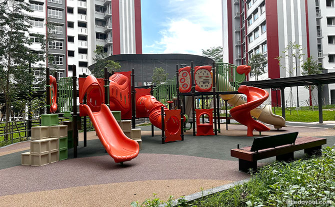 An orange and green play structure with several slides and stepping crates at Westscape.