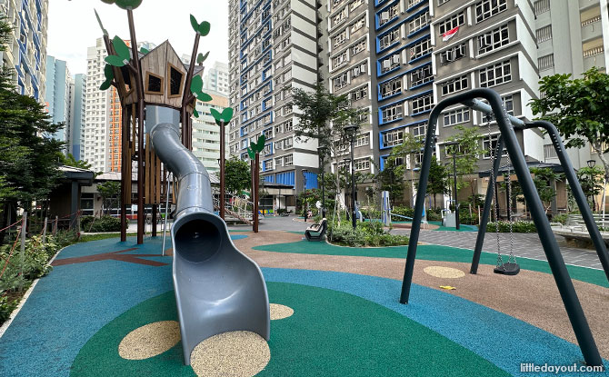A tall green netted treehouse with a grey tube slide at Kallang Breeze.