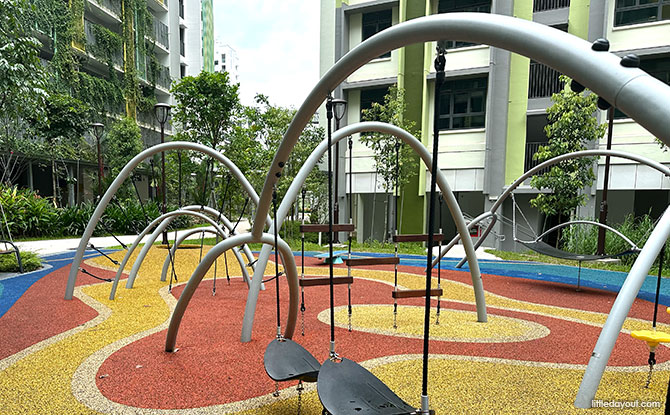 Curved metal climbing frames, ropes and a play mound at Parc Woods in Tengah.