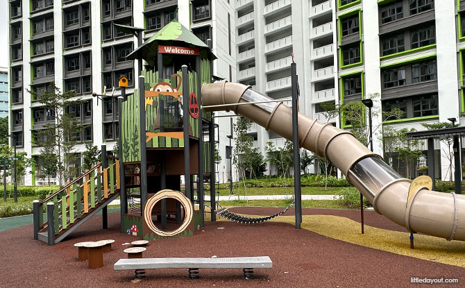 A tall forest-themed climbing tower and long enclosed slide at Woodgrove Ascent.