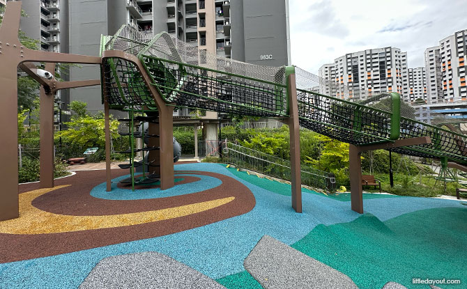 An elevated netted tunnel over blue and green surfacing beside Block 963C.