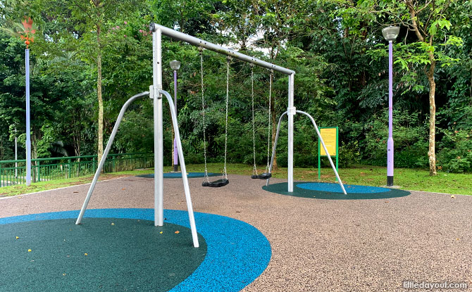 Two swing frames on blue circular play surfacing at Goldhill Avenue Playground.