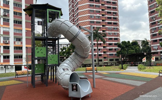 Green play tower and enclosed grey slide in Bishan North Neighbourhood Park.