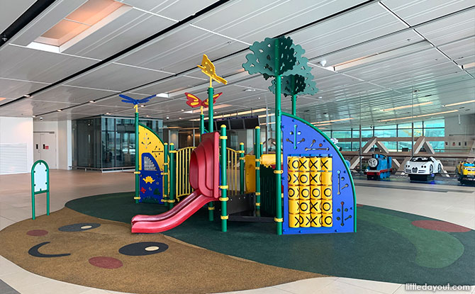 Low pink slides and a yellow tic-tac-toe panel at the Changi Terminal 1 public viewing-gallery playground.