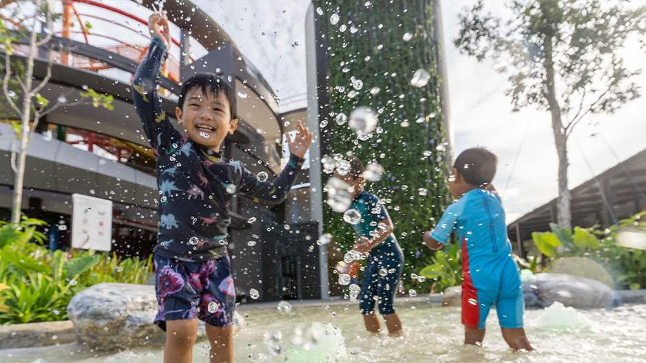 Children playing in the water jets beside Coastal PlayGrove’s tower