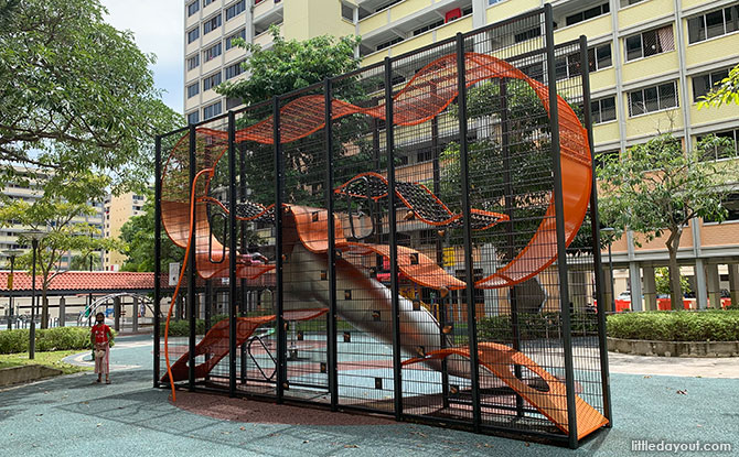 A tall mesh Wallholla climbing structure with curved platforms beside Simei Road.
